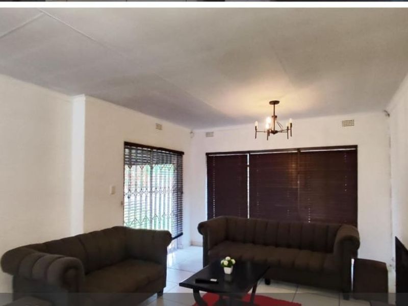 A living room featuring tiled flooring, security gates, and venetian blinds, offering a functional space with potential for cosmetic updates.