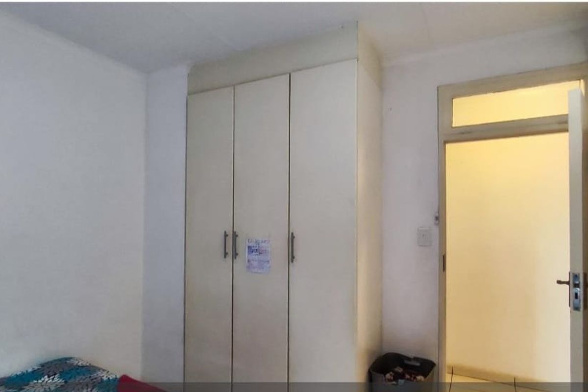 A bedroom featuring a built-in wardrobe and a doorway with a transom window, providing functional storage and access.