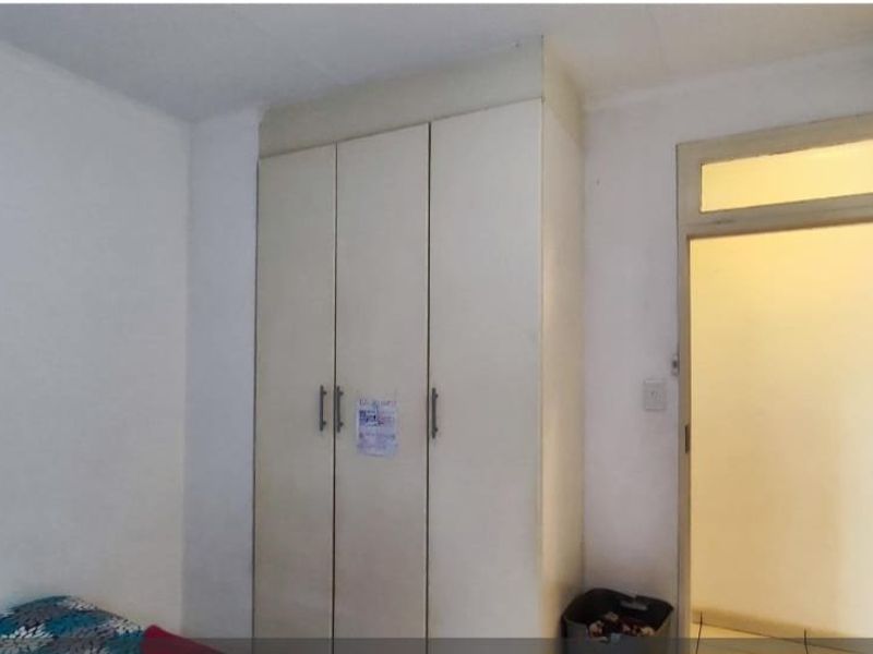 A bedroom featuring a built-in wardrobe and a doorway with a transom window, providing functional storage and access.