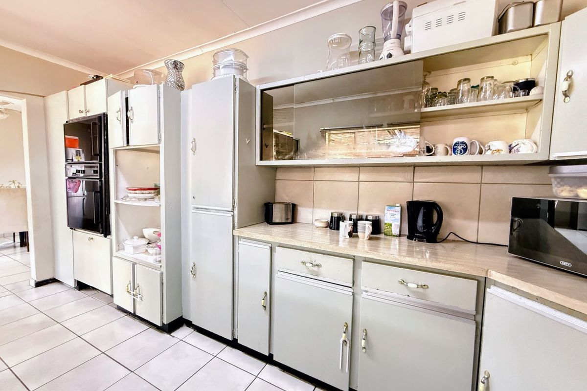 A dated kitchen featuring original built-in cabinetry, tiled flooring, and a tiled backsplash, offering significant potential for a modern renovation.