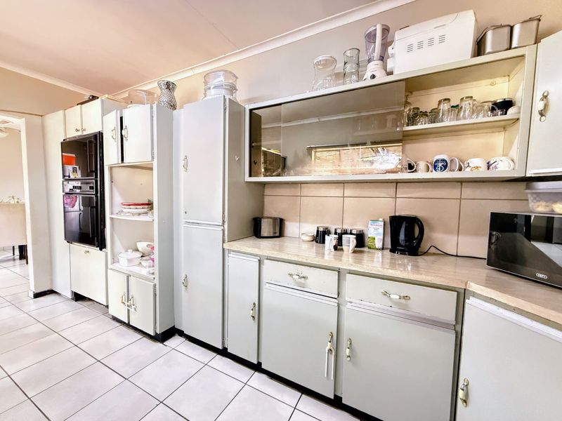 A dated kitchen featuring original built-in cabinetry, tiled flooring, and a tiled backsplash, offering significant potential for a modern renovation.