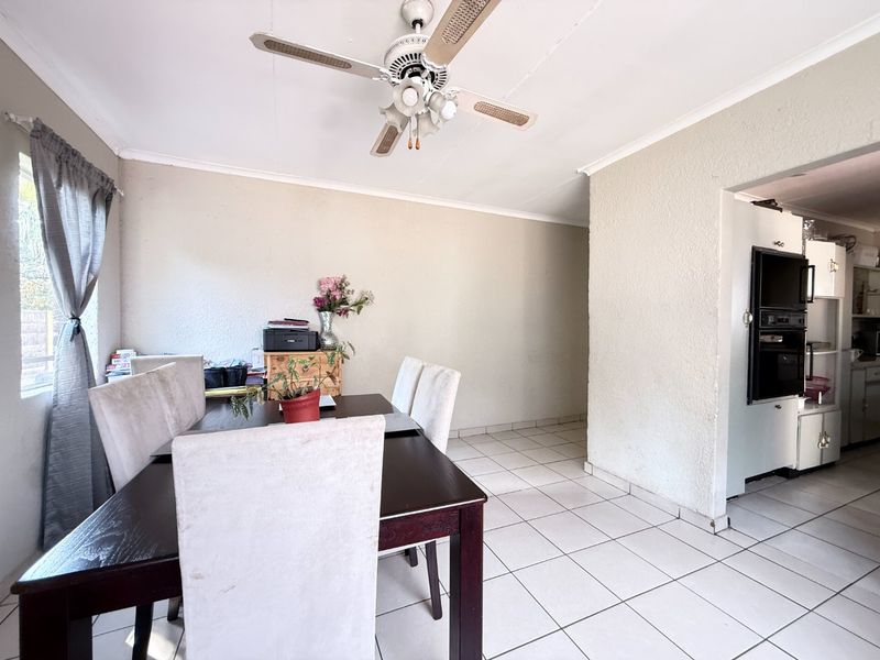 Dining area featuring tiled flooring and a ceiling fan, with an adjacent kitchen space visible containing built-in oven and cabinetry.
