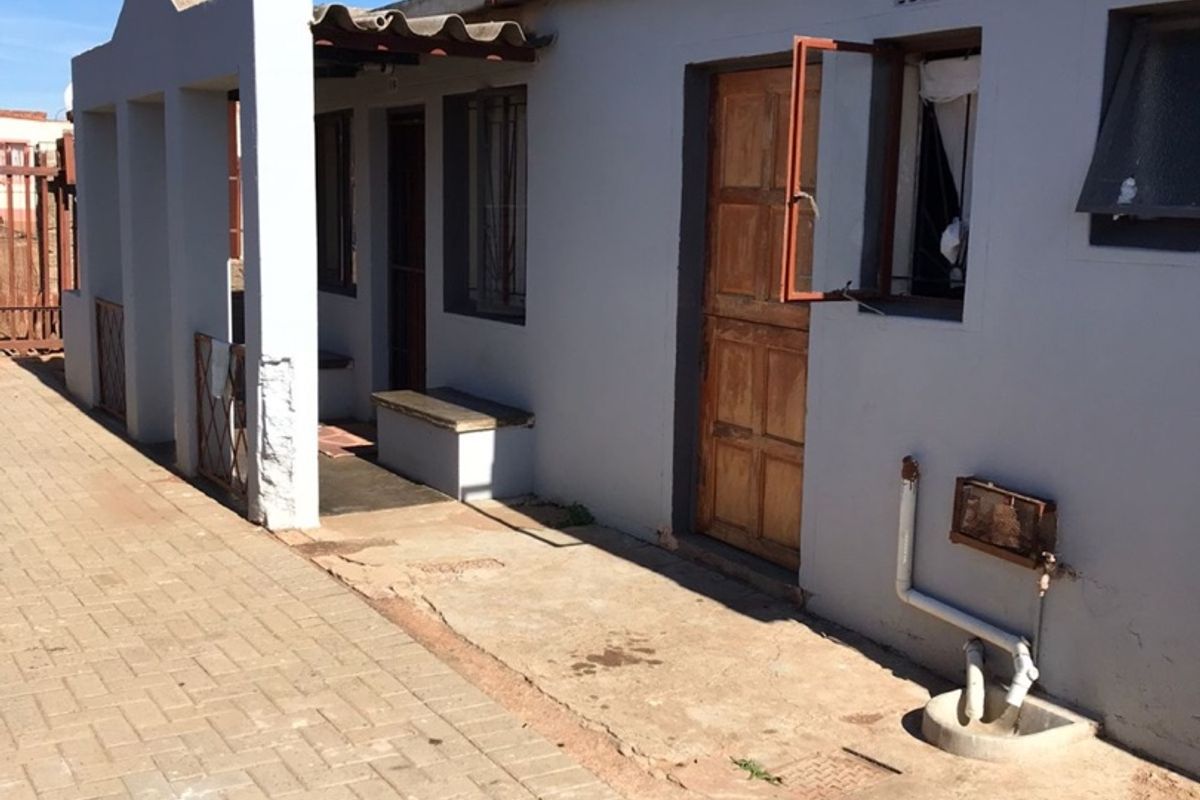 Rear exterior view of the property featuring a paved area, concrete patio, and access to the main building structure.