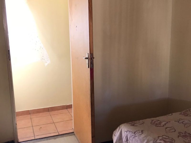 A bedroom featuring tiled flooring and an internal door leading to an adjacent space, requiring cosmetic updates to improve the overall finish.
