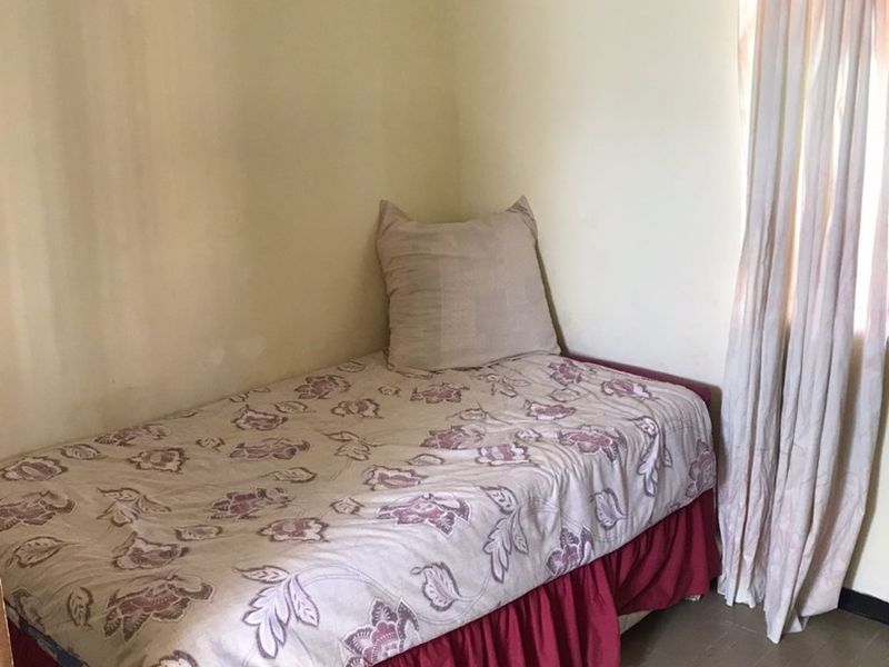 A compact bedroom featuring neutral wall paint, a window with curtain rail, and basic flooring, offering a blank canvas for potential updates.