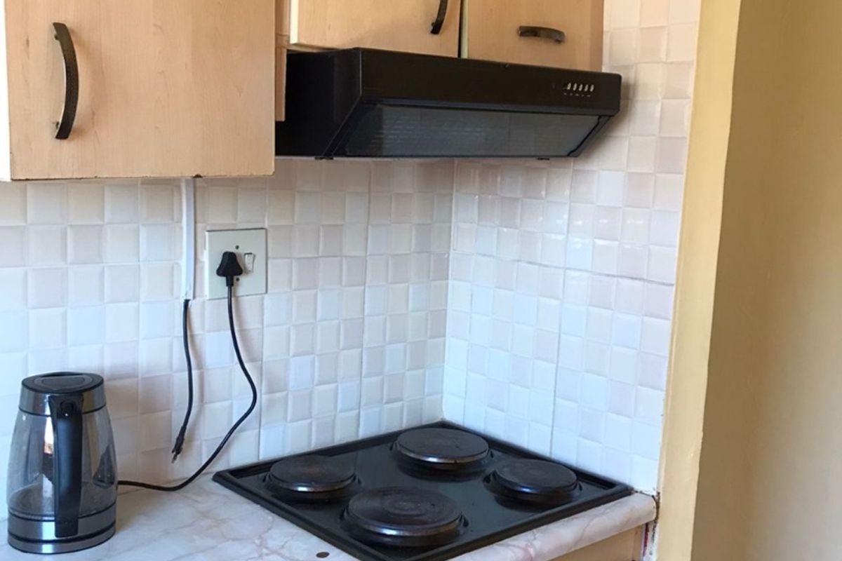 A functional kitchen area featuring built-in cabinetry, a tiled backsplash, and integrated cooking appliances including an electric hob and oven.