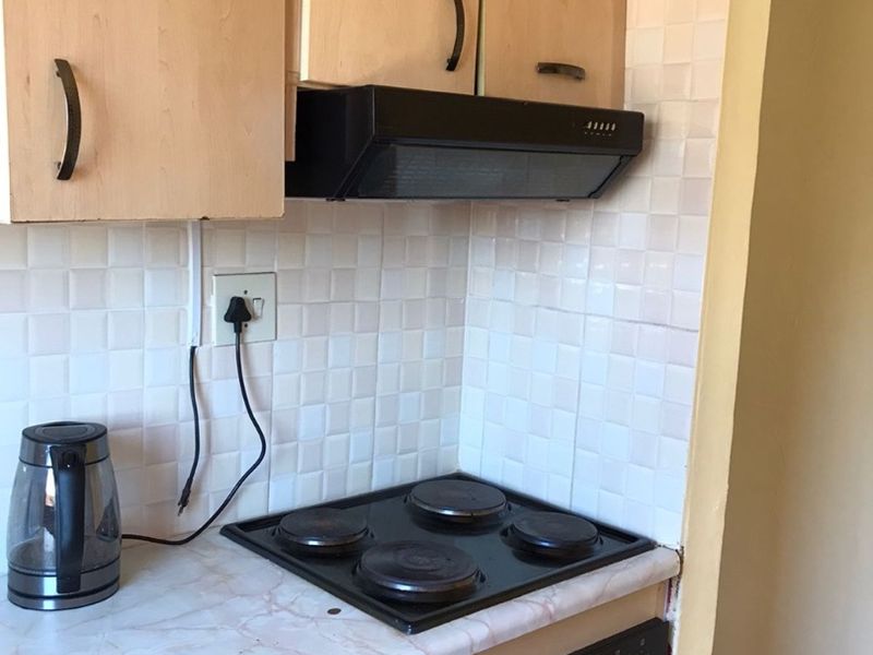 A functional kitchen area featuring built-in cabinetry, a tiled backsplash, and integrated cooking appliances including an electric hob and oven.