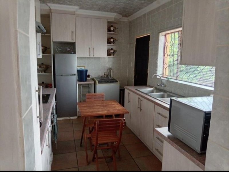 Functional kitchen featuring built-in cabinetry, double basin sink, tiled finishes, and direct access to the exterior.