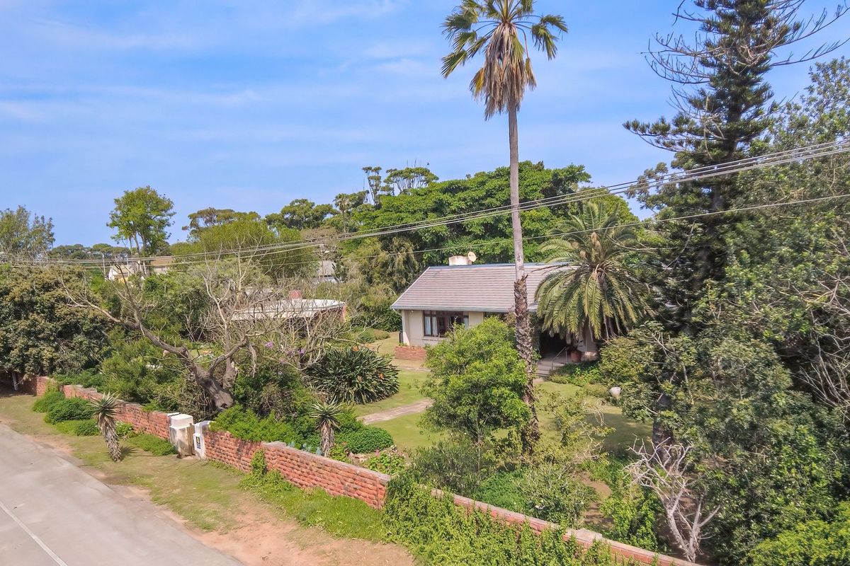 Aerial view of a residential property featuring a tiled roof house, established garden, and brick boundary wall along the street frontage.