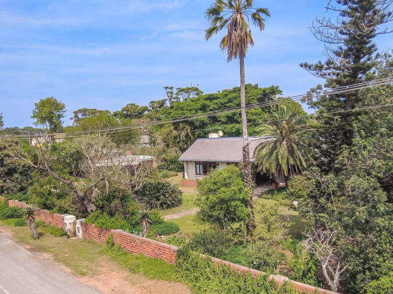 Aerial view of a residential property featuring a tiled roof house, established garden, and brick boundary wall along the street frontage.
