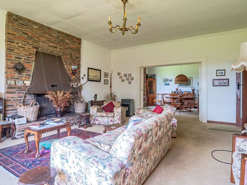 Spacious living room featuring a prominent brick fireplace with a metal hood, decorative ceiling rose, and coving, leading into an adjacent dining area.