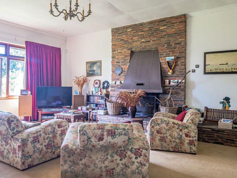 Spacious living room featuring a prominent brick fireplace with a metal hood, stone hearth, and large timber-framed windows.