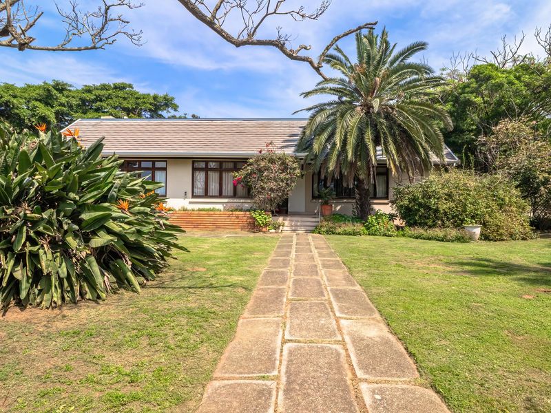 Front view of a single-story house featuring a paved walkway leading to the entrance, timber decking, and a well-maintained garden.