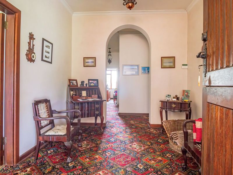 A traditional entrance hall featuring a solid timber front door, arched interior doorway, and patterned carpet flooring.