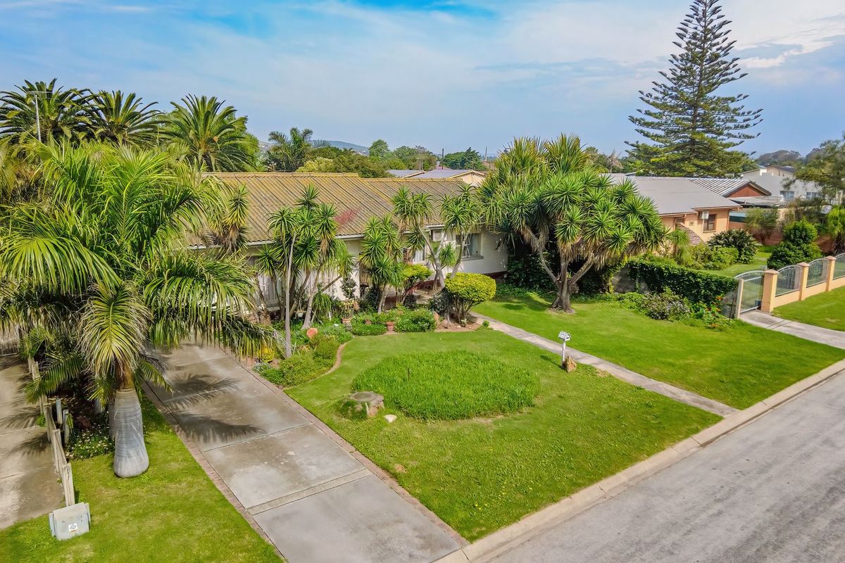 Aerial view of a residential property featuring a concrete driveway, established garden, and tiled roof structure.