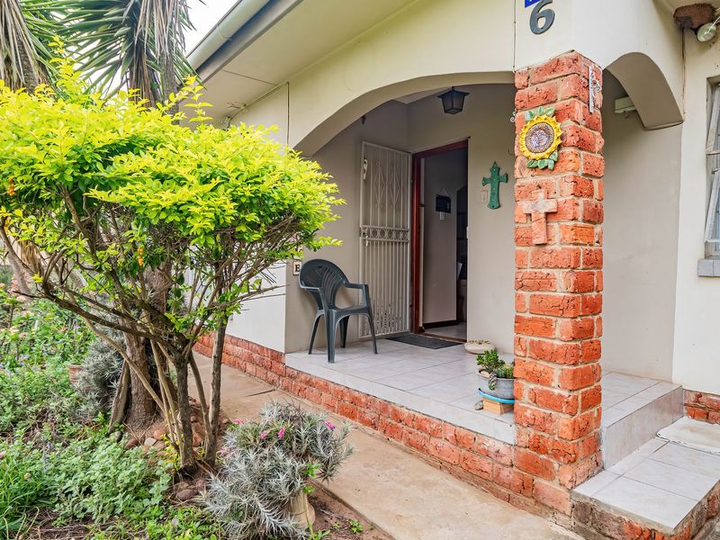 Front entrance porch featuring a brick pillar, tiled flooring, and security gate access to the home.