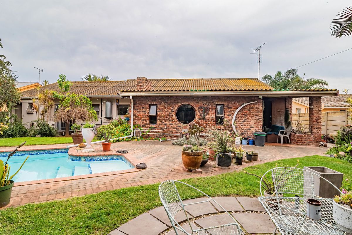 Rear exterior view featuring a swimming pool, paved patio area, and a brick facade with a distinctive circular window.