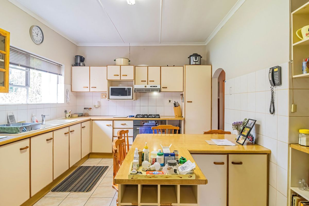A functional kitchen featuring light-toned cabinetry, laminate countertops, tiled backsplash, and integrated appliances, offering a practical layout with ample storage space.