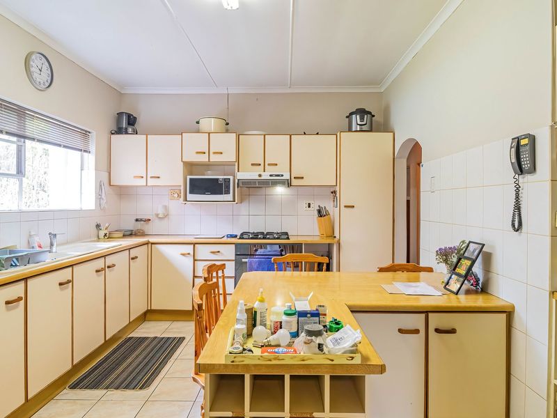 A functional kitchen featuring light-toned cabinetry, laminate countertops, tiled backsplash, and integrated appliances, offering a practical layout with ample storage space.
