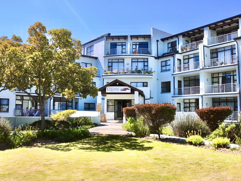 Front elevation of the Equini apartment complex featuring a landscaped garden, covered entrance, and multiple levels with private balconies.