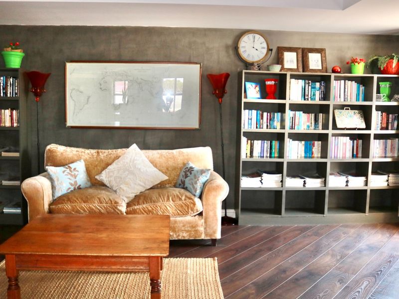 A cozy living room featuring dark laminate flooring, a feature wall with built-in shelving units, and a recessed ceiling design.