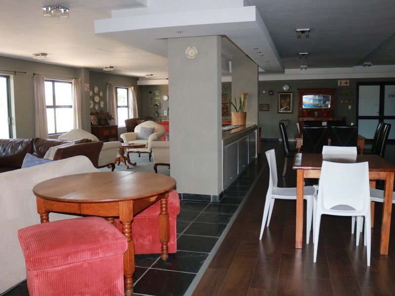 Spacious open-plan living and dining area featuring a mix of tiled and laminate flooring, a central structural column, and recessed ceiling lighting.