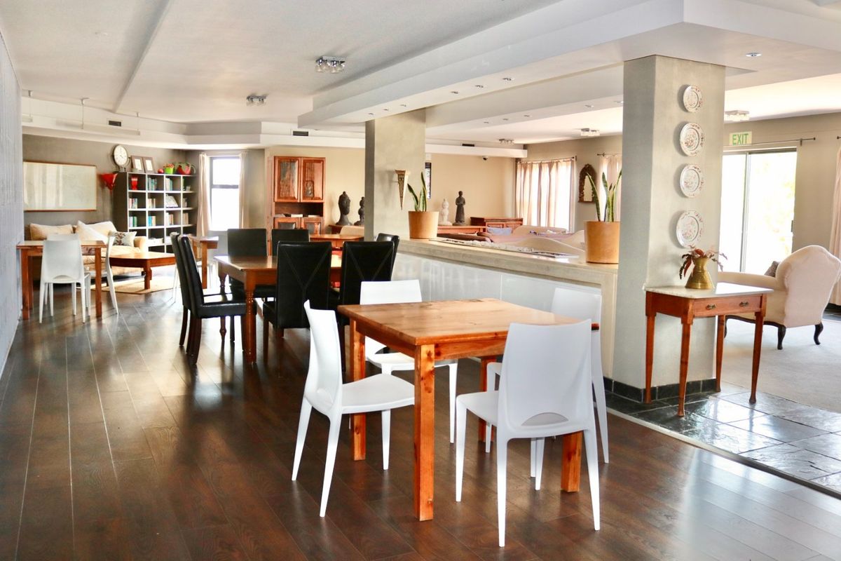 Spacious open-plan living and dining area featuring dark hardwood flooring, recessed lighting, and a central structural column with a low-level partition wall.