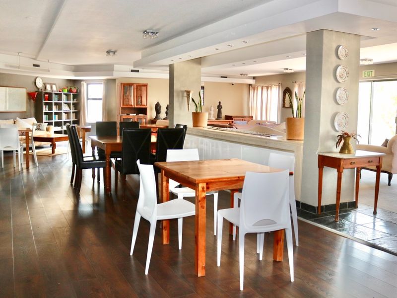 Spacious open-plan living and dining area featuring dark hardwood flooring, recessed lighting, and a central structural column with a low-level partition wall.