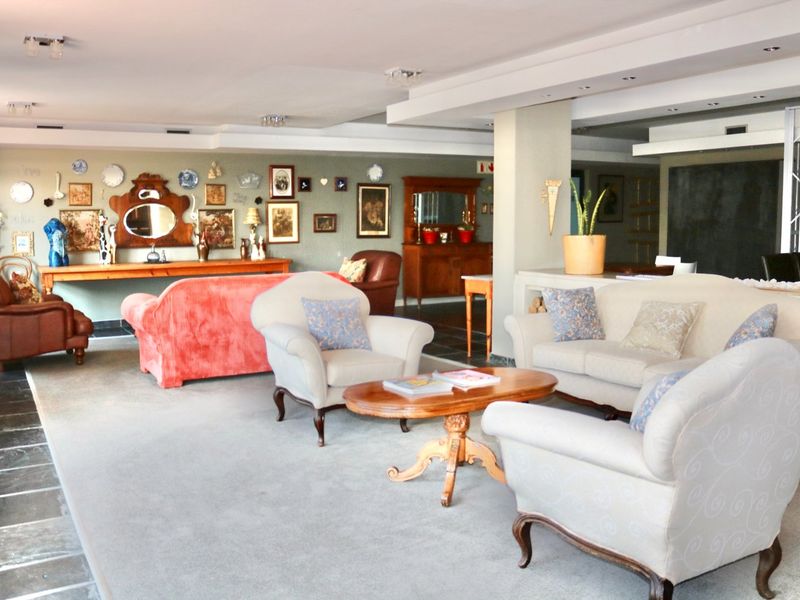 Spacious open-plan living area featuring a mix of tiled and carpeted flooring, recessed ceiling lighting, and a central structural column.
