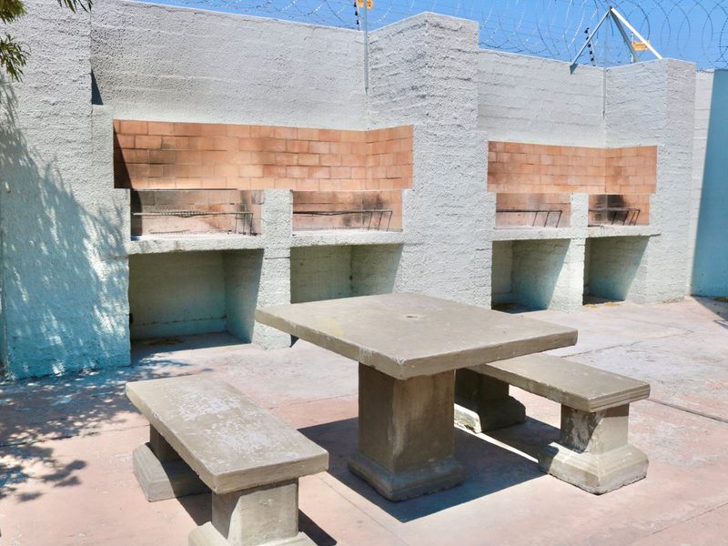 Outdoor entertainment area featuring dual built-in braai stations, concrete seating, and secure perimeter fencing, ideal for communal or private outdoor dining.