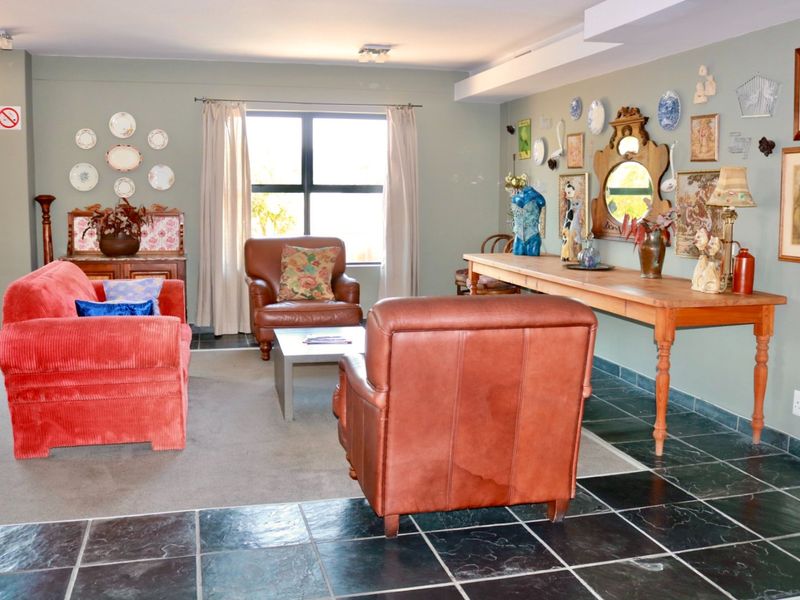 A spacious living room featuring a combination of dark tiled flooring and carpet, neutral wall tones, and natural light from a large window.