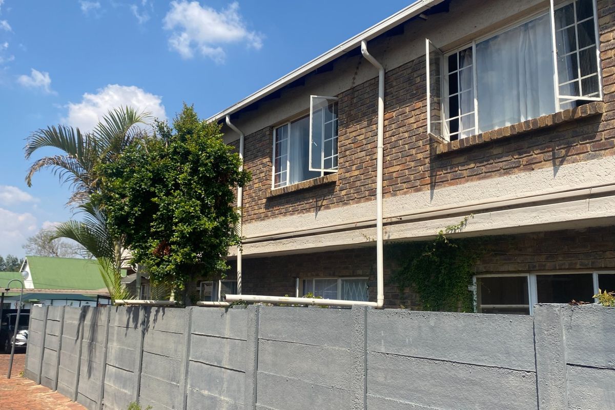 Exterior view of a face brick apartment building featuring casement windows and a precast concrete boundary wall.