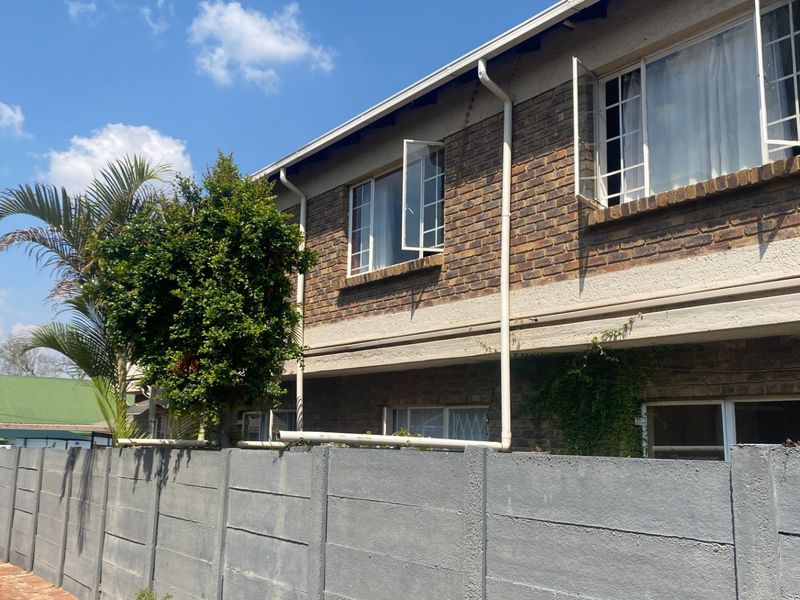 Exterior view of a face brick apartment building featuring casement windows and a precast concrete boundary wall.