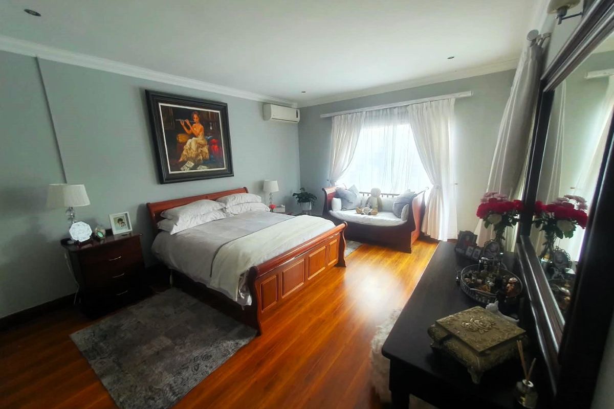 Spacious bedroom featuring polished hardwood flooring, recessed lighting, and a wall-mounted air conditioning unit.