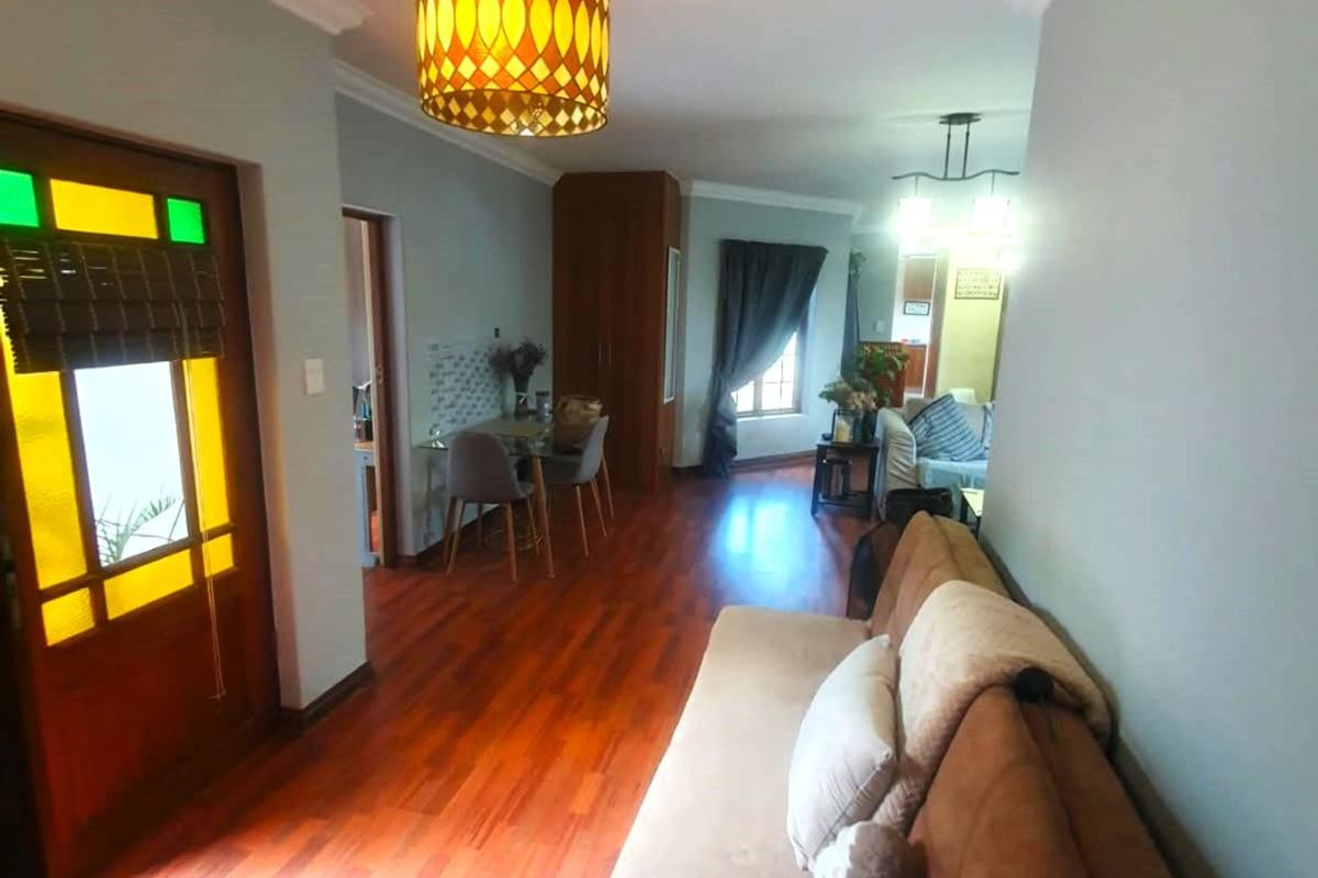 A welcoming living area featuring warm hardwood flooring, crown molding, and a distinctive stained glass front door, creating a bright and inviting entrance space.