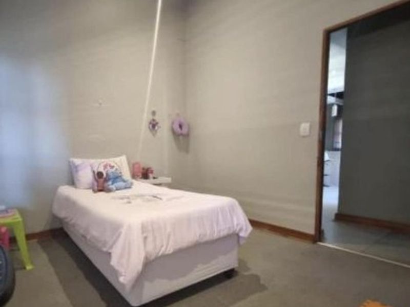 A simple bedroom featuring neutral wall finishes and carpeted flooring, with an internal doorway leading to an adjacent space.