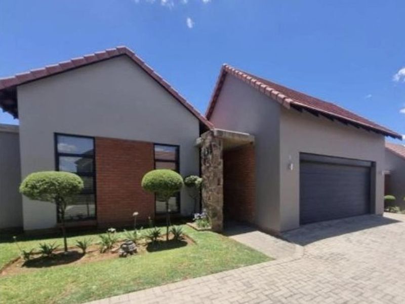 Front elevation of a modern townhouse featuring a combination of brick and stone cladding, a tiled roof, and an integrated single garage.