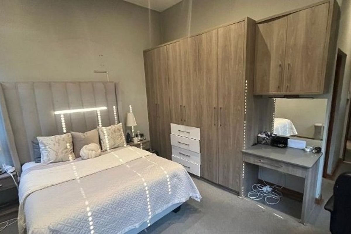 A well-appointed bedroom featuring extensive built-in wooden cabinetry, integrated storage, and a dedicated vanity area with mirror.