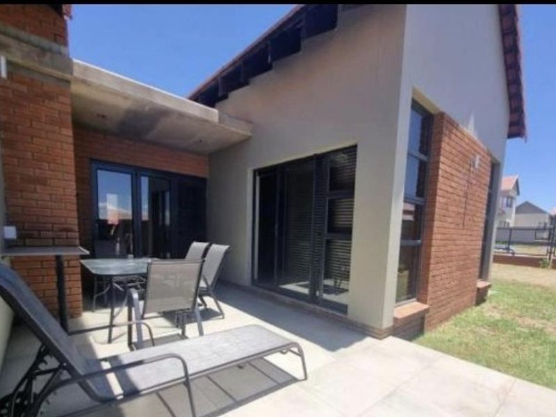 Rear exterior view of the townhouse featuring a tiled patio, sliding glass doors, and exposed brick facade with visible roof maintenance required.