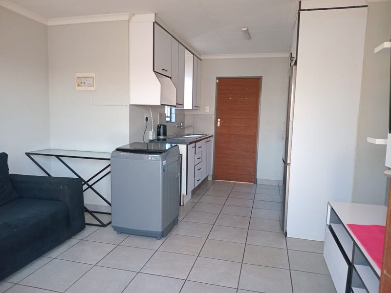 Open plan living area featuring tiled flooring and a compact kitchen space with built-in cabinetry and an extractor fan.