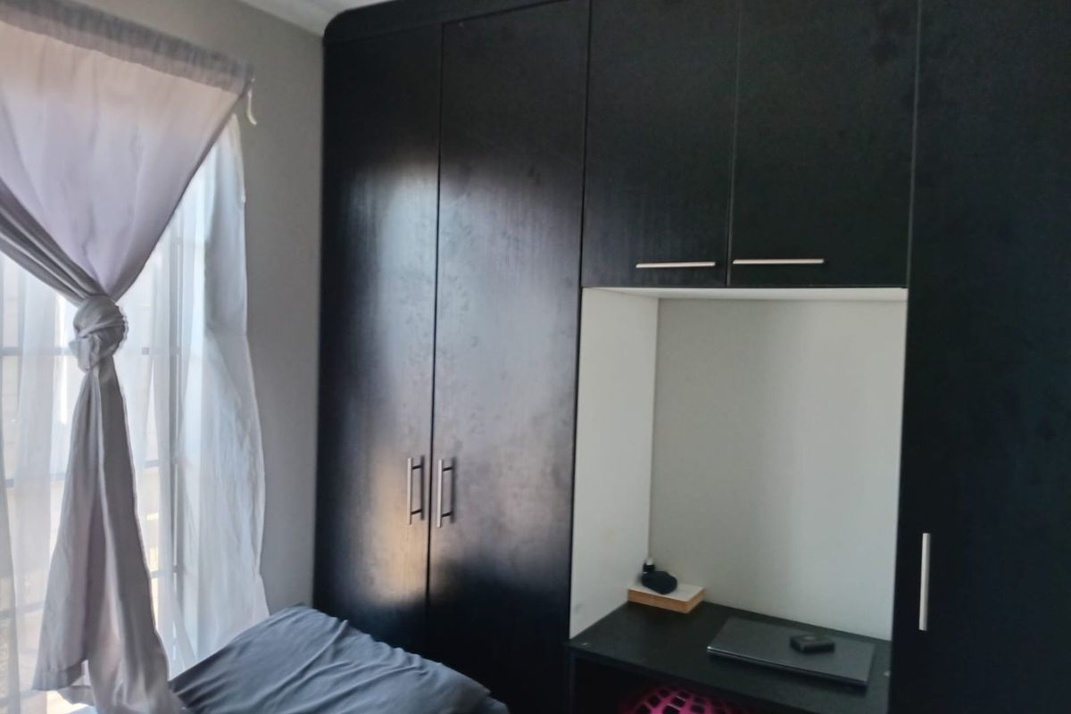 A bedroom featuring dark built-in cupboards with an integrated desk area, providing functional storage and workspace.