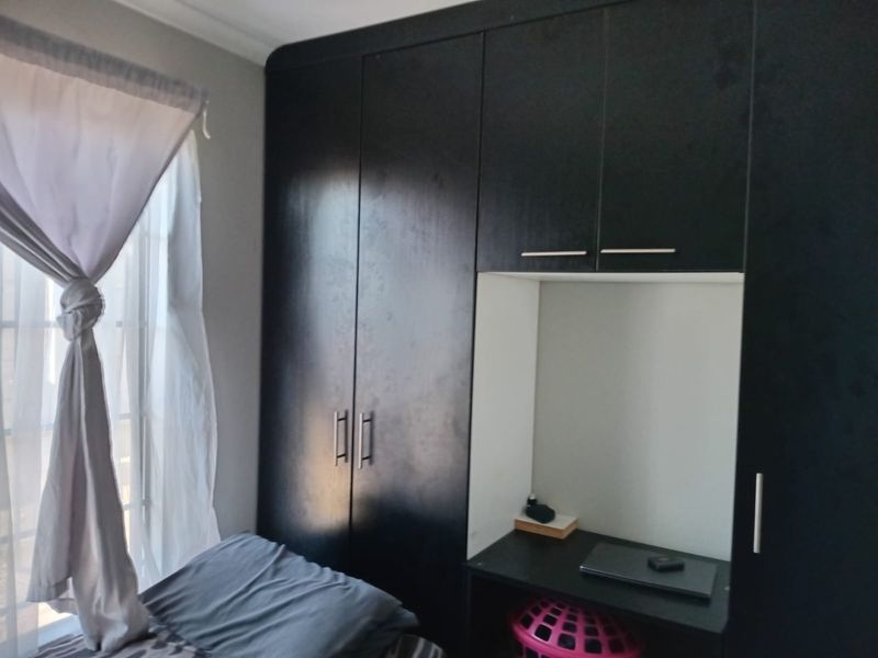 A bedroom featuring dark built-in cupboards with an integrated desk area, providing functional storage and workspace.