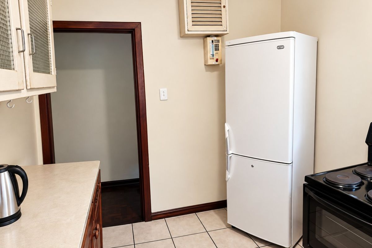 A functional kitchen area featuring built-in cabinetry, tiled flooring, and an integrated stove, offering a practical layout for daily meal preparation.