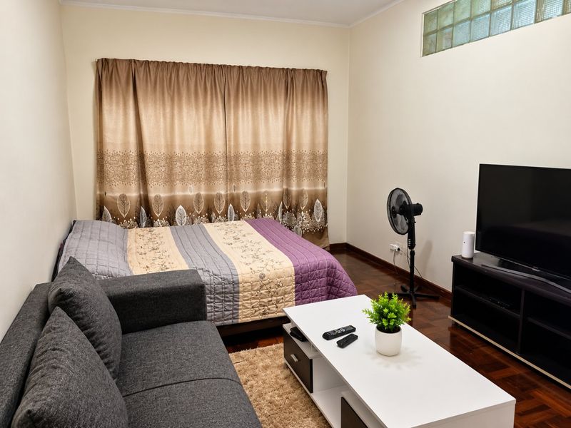 A bedroom featuring hardwood flooring and a high-level glass block window, providing a functional space with neutral wall finishes.