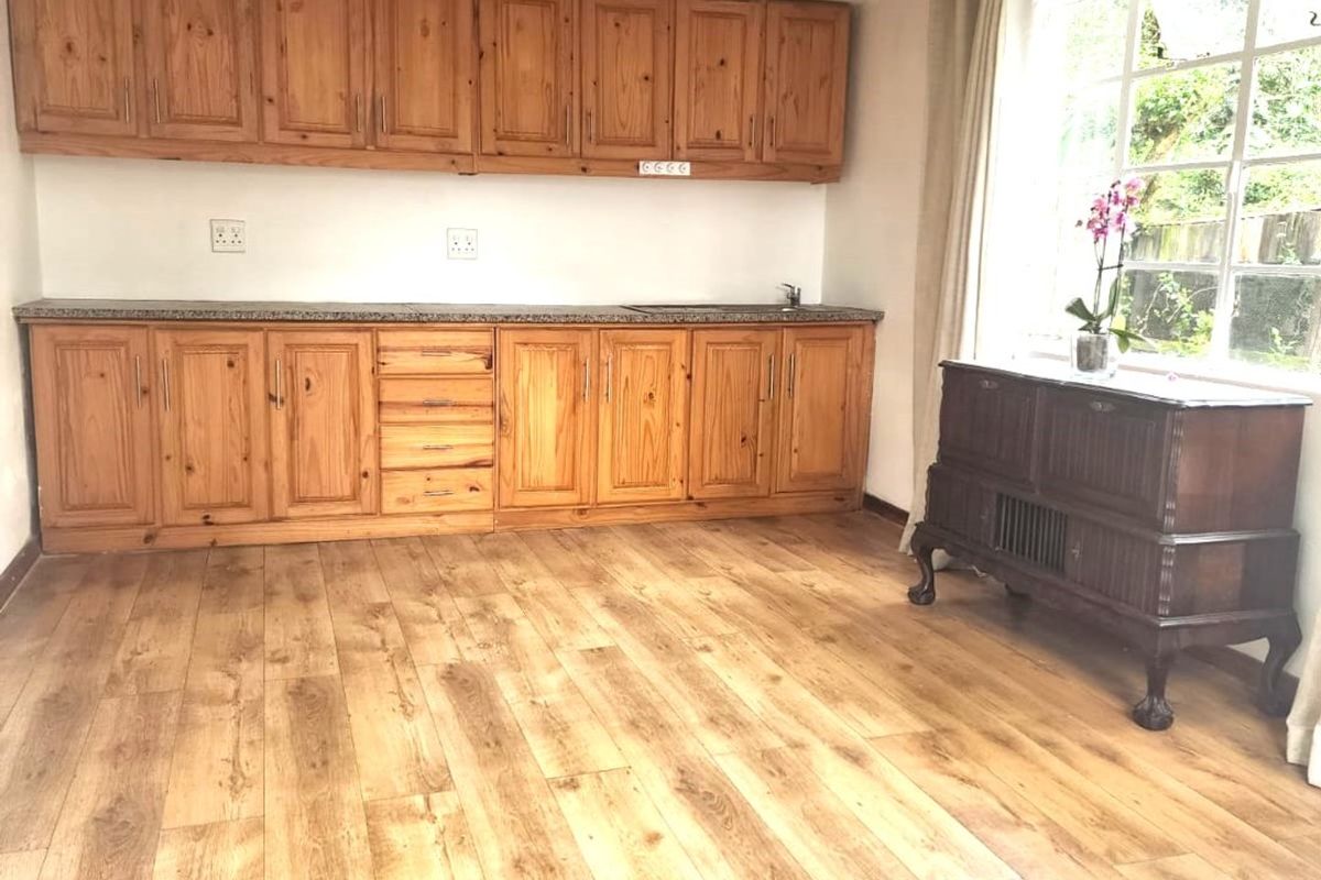 A kitchen area featuring wooden cabinetry, granite countertops, and laminate flooring, offering a functional space with natural light from the window.