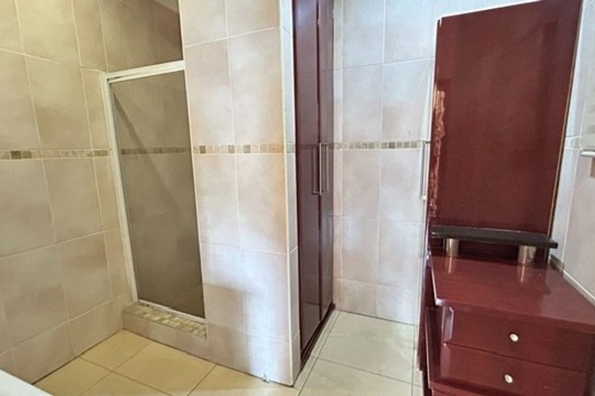 A bathroom featuring a shower enclosure with tiled walls and floor, complemented by built-in cabinetry.