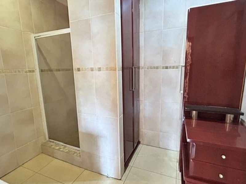 A bathroom featuring a shower enclosure with tiled walls and floor, complemented by built-in cabinetry.