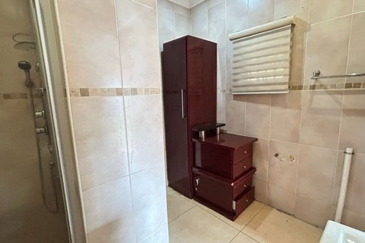 A tiled bathroom featuring a shower enclosure and wall-mounted towel rail, currently requiring completion of vanity or basin installation.