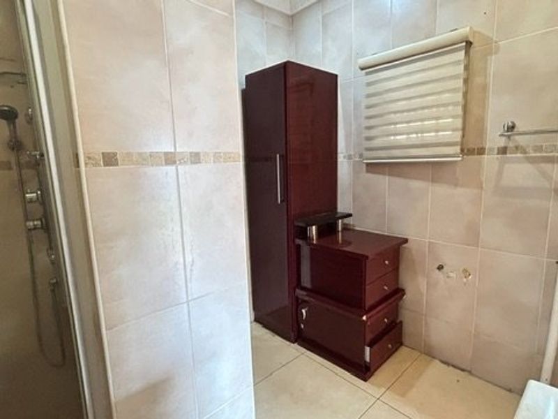 A tiled bathroom featuring a shower enclosure and wall-mounted towel rail, currently requiring completion of vanity or basin installation.