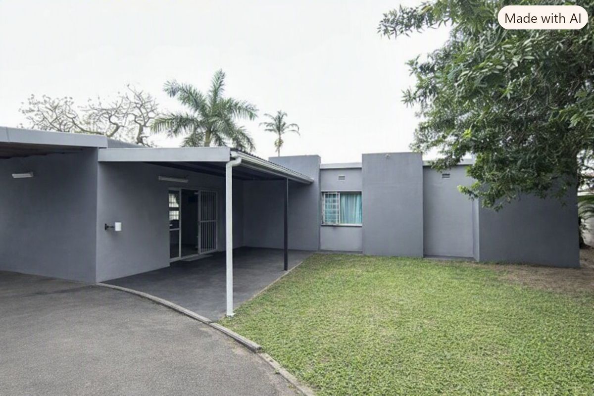 Rear view of the property featuring a covered patio area, paved driveway, and a well-maintained lawn.